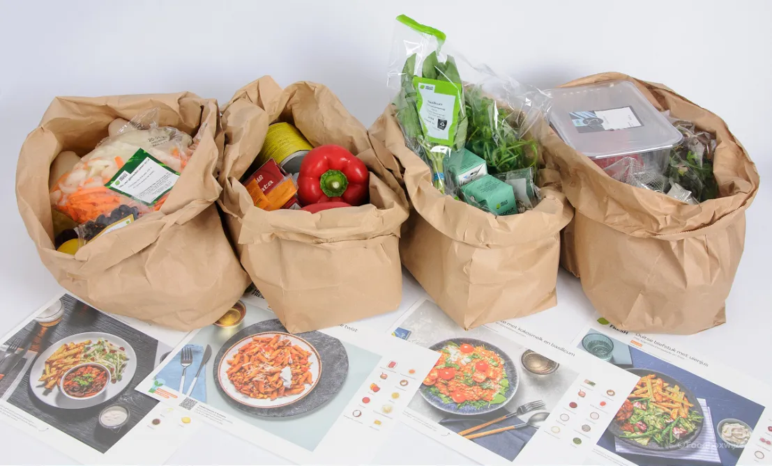 4 receptkaarten op onze tafel met daarachter een zak met alle producten behorend bij het gerecht