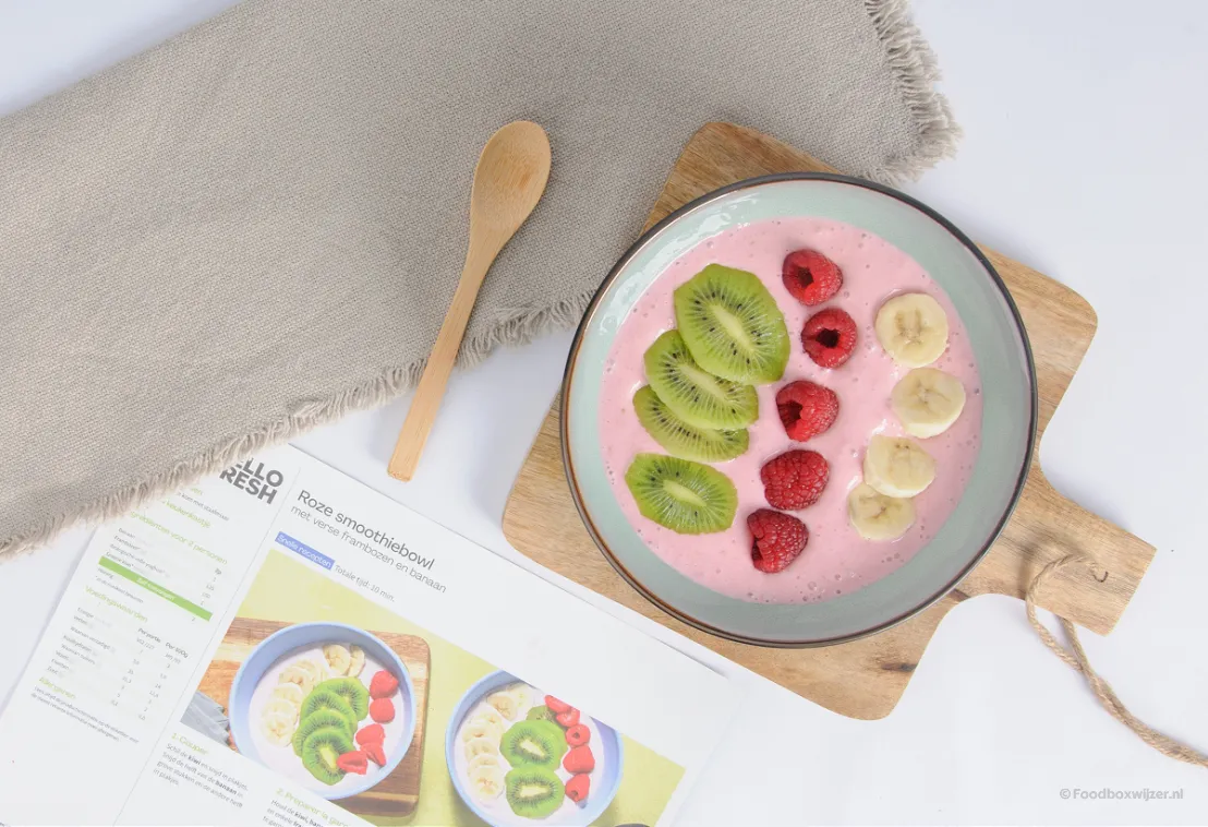 Een lekkere smoothiebowl met vers fruit zoals kiwi en frambozen geserveerd in een kommetje.