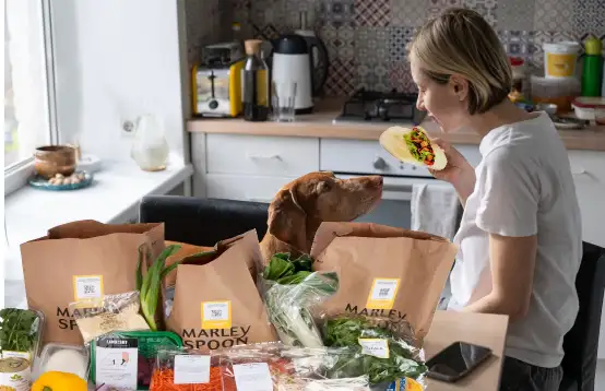 Een vrouw met hond die een eenpersoonsmaaltijd eet