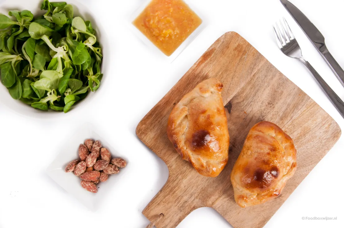 De empanada's met kazige mais op een plank op tafel