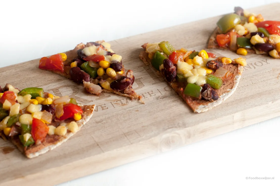 Puntjes Mexicaanse tortillapizza die we gemaakt hebben op een houten serveerplank
