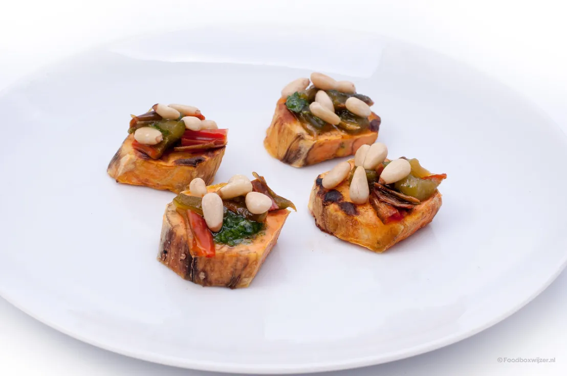 Een bord met toast van zoete aardappel met paprika en pijnboompitten