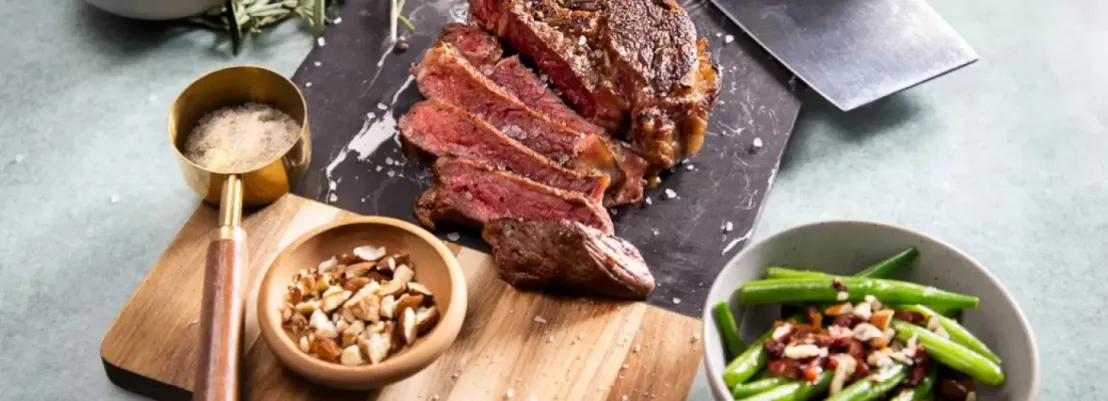 Op een bord en plank een bereidde entrecote van Gruttovlees met grof zeezout en rozemarijn
