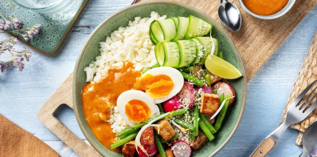 gado gado bowl met bloemkoolrijst geserveerd in een kommetje op een houten plank