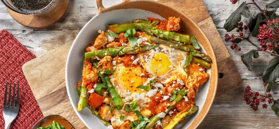 Shakshuka op een koolhydraatarme manier gemaakt met groene asperges en geserveerd op een mooi gedekte tafel