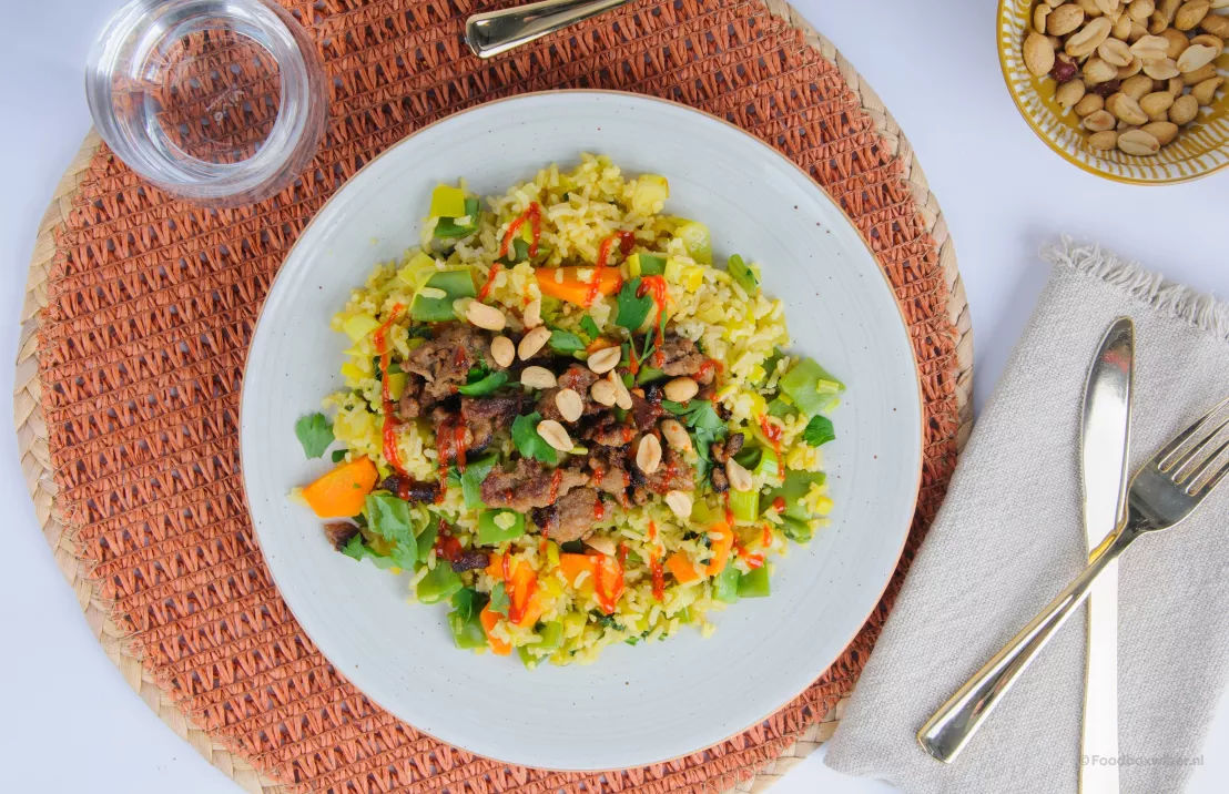 Gerecht van crisp weekbox van spicy nasi goreng met extra groenten zoals snijbonen, wortel en prei