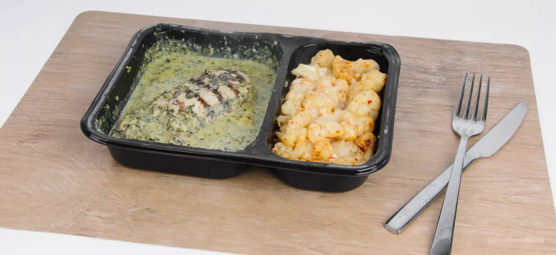 Een gerecht met kip en bloemkool van Factor waarvan wel de smaak lekker is, maar het gerecht er niet opgewarmd nog niet meteen heel smakelijk uit ziet in het zwarte bakje.