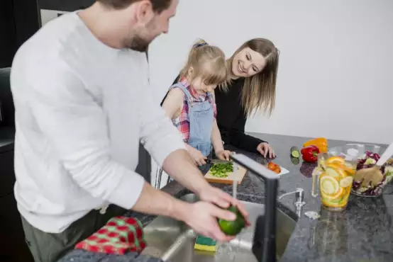 Man en vrouw zijn samen met een kind een gezonde maaltijd aan het bereiden
